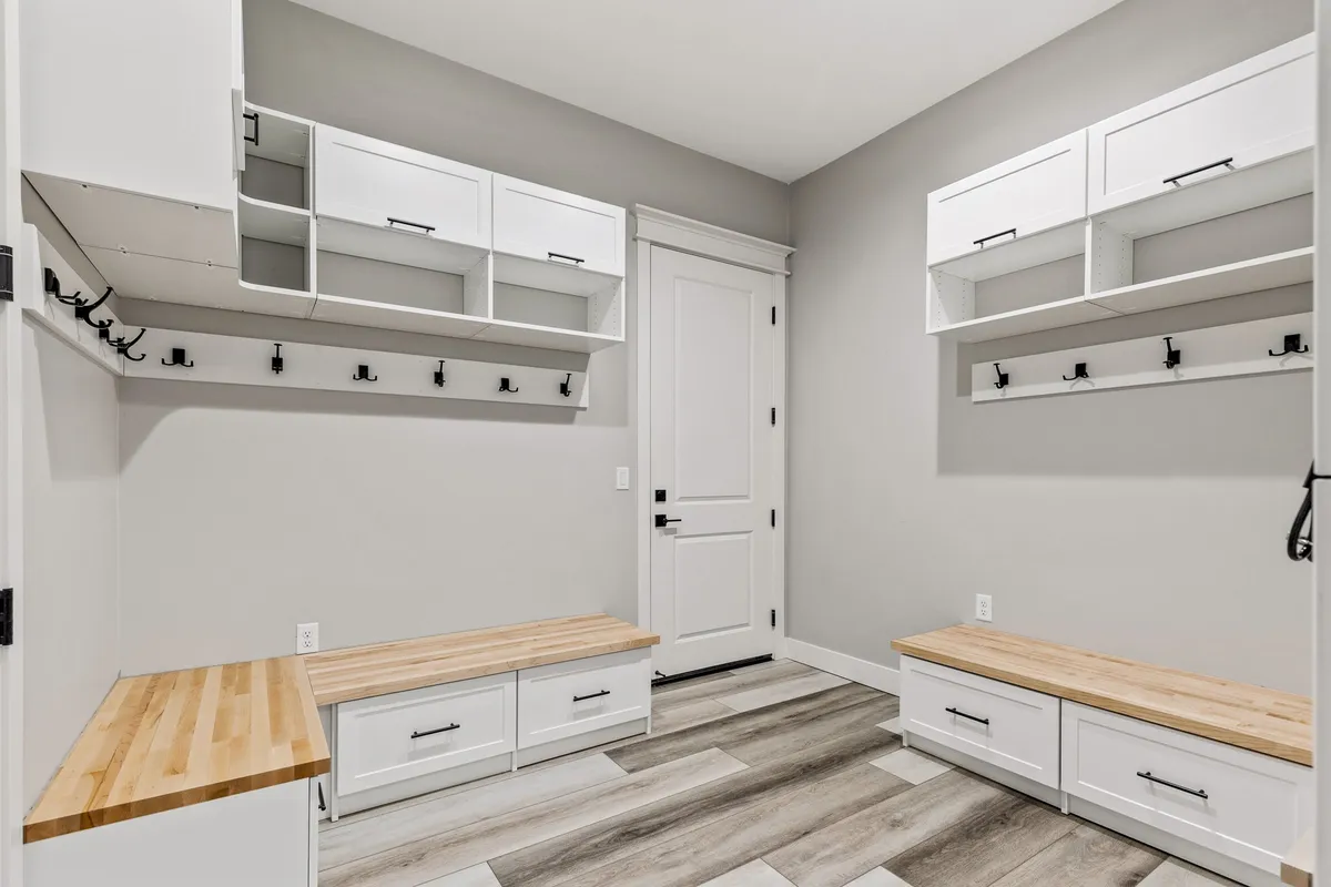 A practical mudroom with built-in benches, storage cabinets, and wall hooks for coats and gear. The space is organized and bright, providing a smooth transition between the outdoors and the rest of the home.