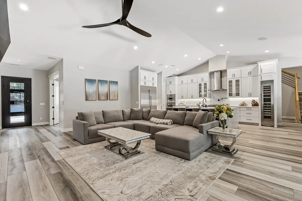 An open-plan living area with a large sectional sofa, coffee table, visible kitchen area, and contemporary artwork. The spacious layout is ideal for relaxing, entertaining, or informal meetings, with a welcoming modern atmosphere.