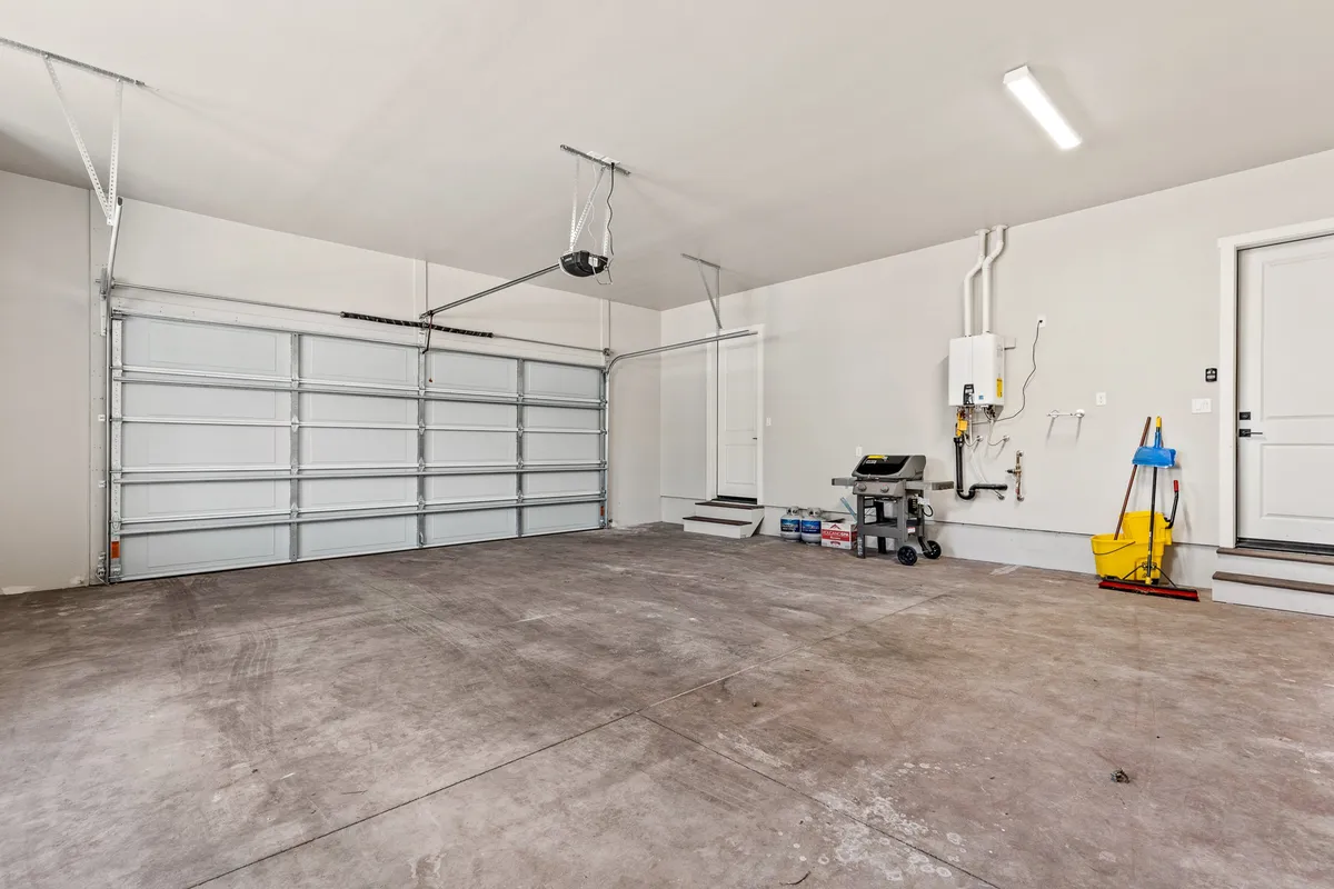 A well-kept attached garage with a visible garage door, workbench, and utility area for storage and projects. The space is clean and functional, offering secure parking and extra storage for gear.